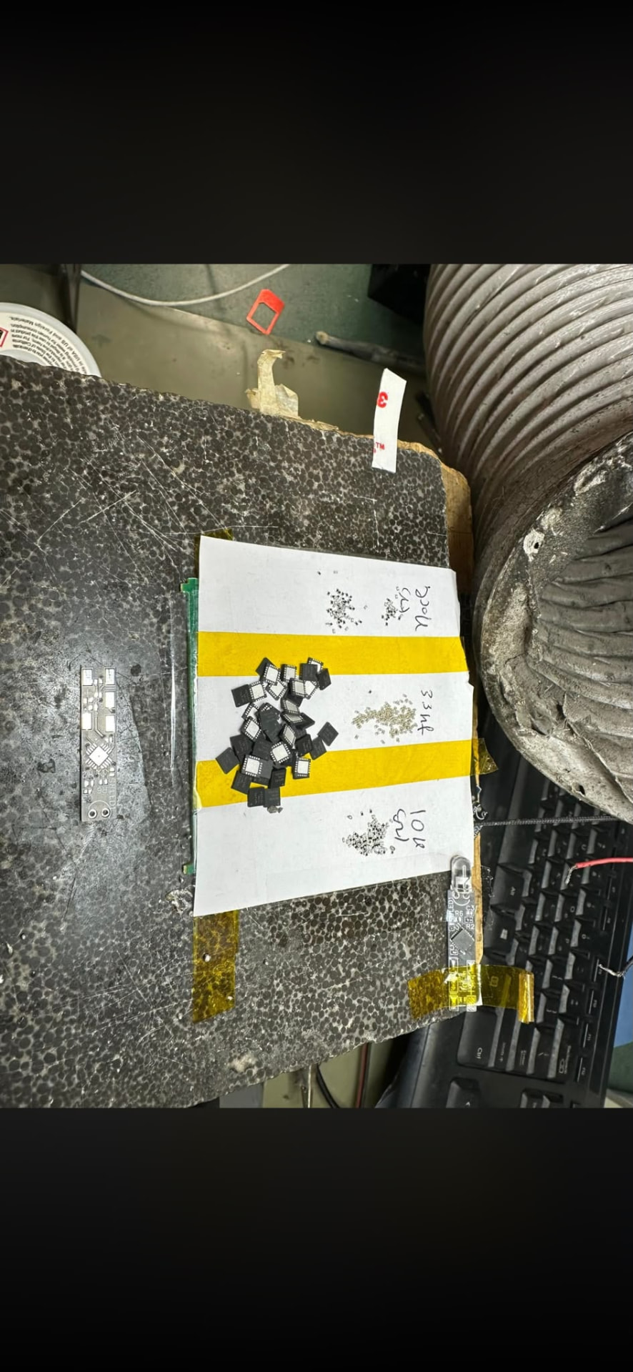 רכיבי QFN ו-SMD זעירים ממוינים על סרט לצד כרטיס PCB ריק